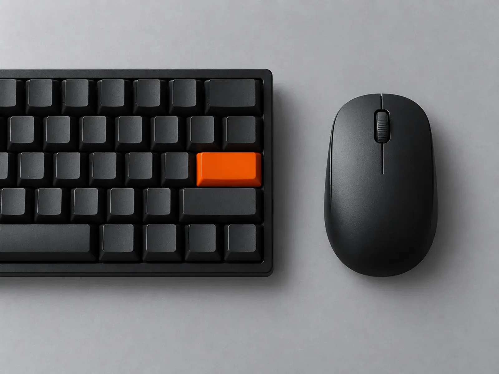 A mechanical keyboard with one orange key next to a computer mouse
